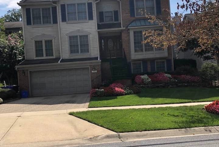 Front yard with edged lawn and flower beds in front of a two-story home