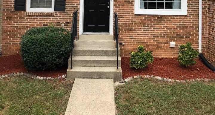 Townhouse entry with trimmed shrubs and red mulch beds